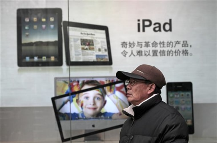 In this file photo taken on Jan. 26, 2011, a man stands near Apple's iPad advertisement in Shanghai, China.